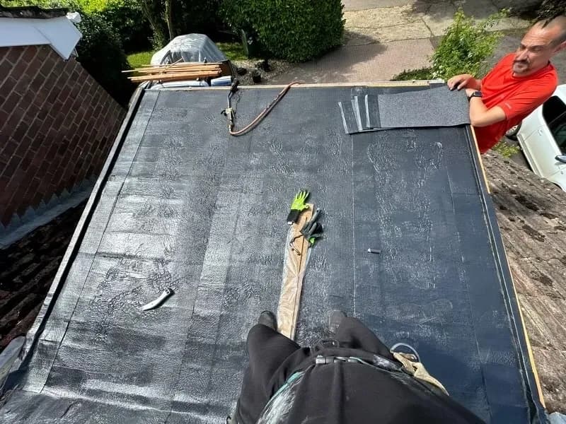Roofer laying torch-on felt membrane
