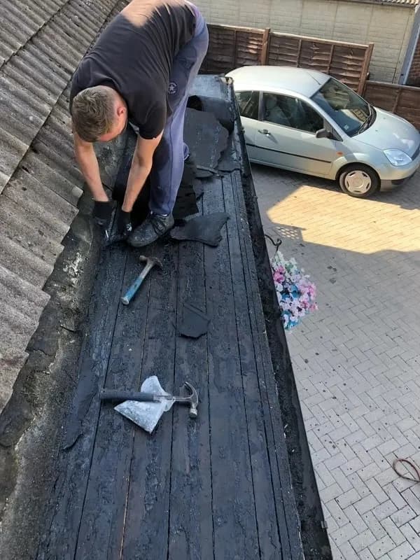 Roofer stripping old felt during flat roof repair
